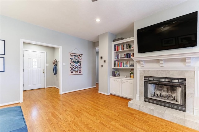 unfurnished living room featuring light hardwood / wood-style floors and a tile fireplace