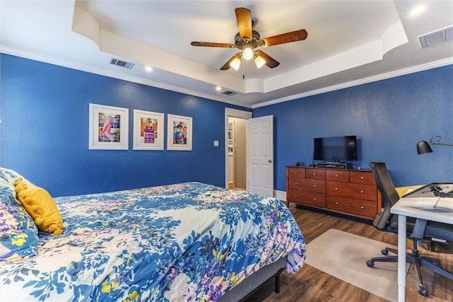 bedroom with a raised ceiling, crown molding, and dark hardwood / wood-style flooring