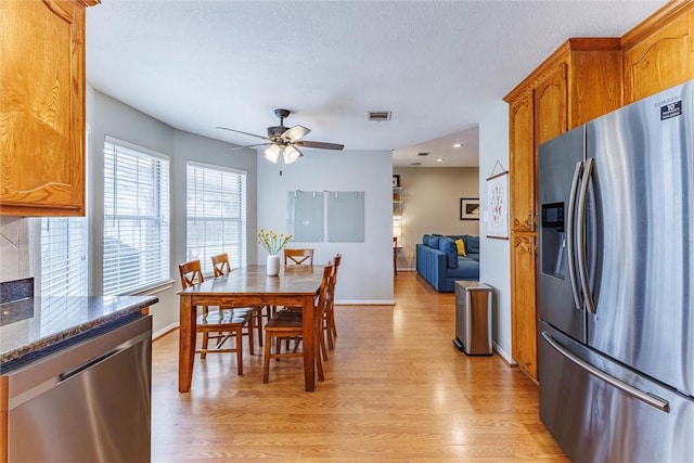 dining area with ceiling fan, light hardwood / wood-style floors, and a textured ceiling