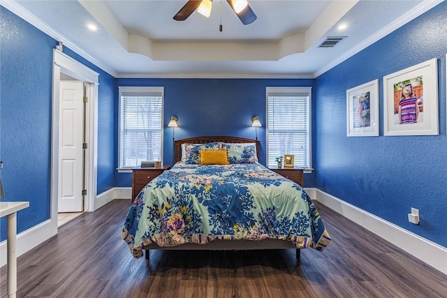 bedroom featuring dark wood-type flooring, ornamental molding, a raised ceiling, and ceiling fan