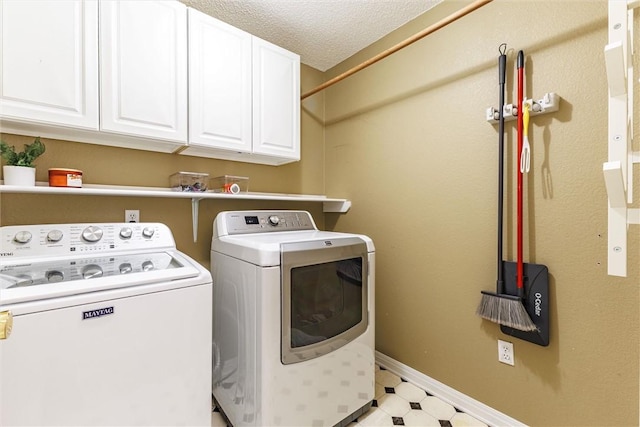 washroom featuring cabinets, washing machine and dryer, and a textured ceiling