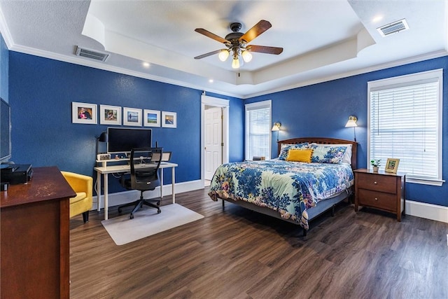 bedroom featuring dark hardwood / wood-style floors, a tray ceiling, and multiple windows