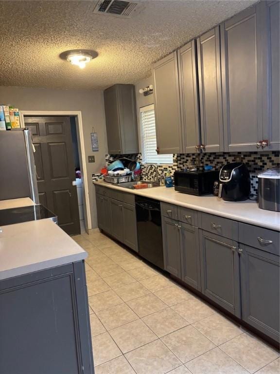 kitchen featuring backsplash, gray cabinetry, light tile patterned floors, a textured ceiling, and black appliances