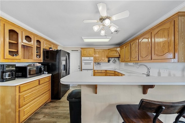 kitchen with a kitchen breakfast bar, kitchen peninsula, sink, and dark wood-type flooring