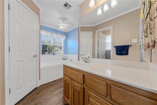 bathroom featuring crown molding, ceiling fan, a relaxing tiled tub, and hardwood / wood-style flooring