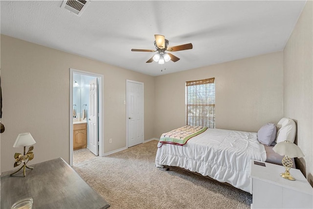 bedroom featuring ceiling fan, light colored carpet, and ensuite bath