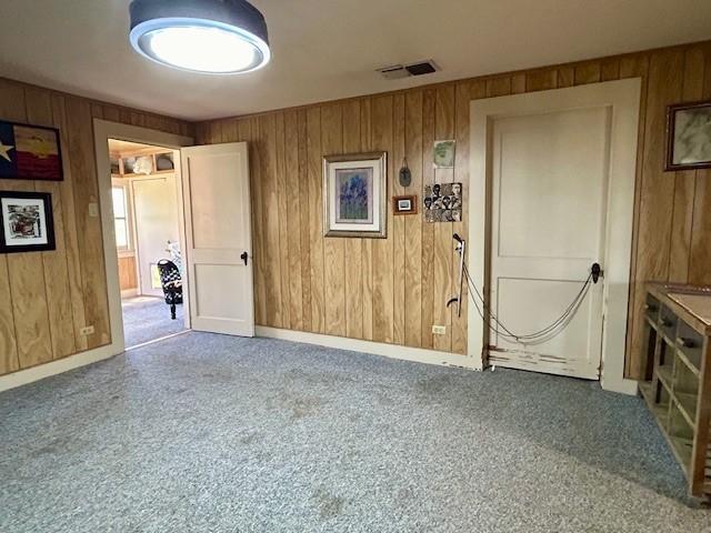 carpeted spare room with wood walls