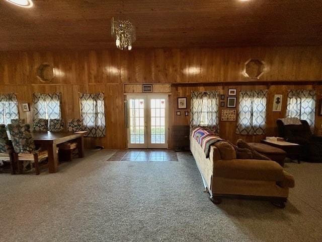 living room featuring carpet flooring, wooden walls, wooden ceiling, and a notable chandelier