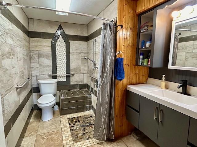 bathroom featuring a shower with curtain, vanity, toilet, and wood walls