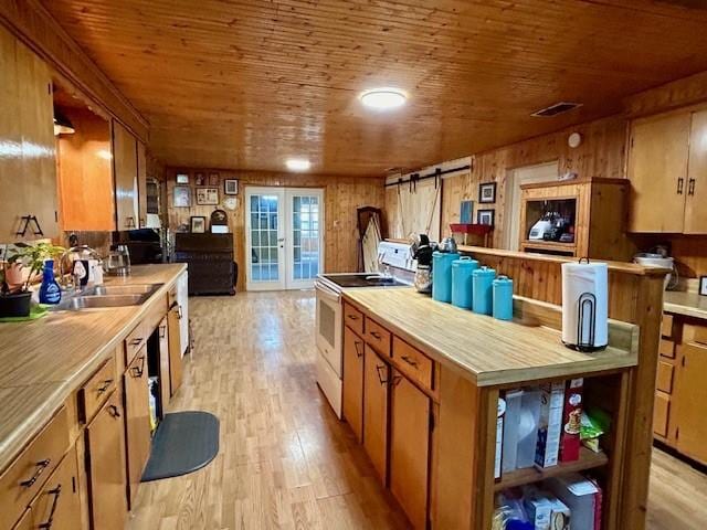 kitchen featuring a barn door, light hardwood / wood-style flooring, electric stove, wooden walls, and wood ceiling