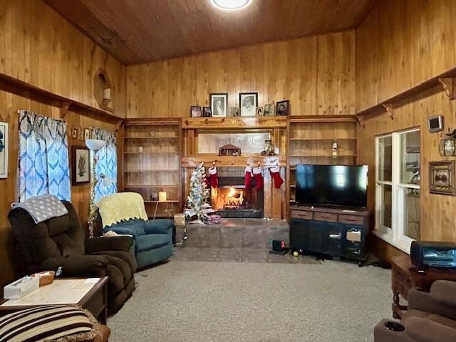 carpeted living room with a fireplace, wooden walls, and wood ceiling