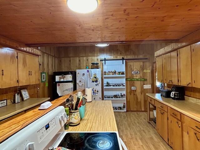 kitchen with wood walls, wood ceiling, white refrigerator, and range