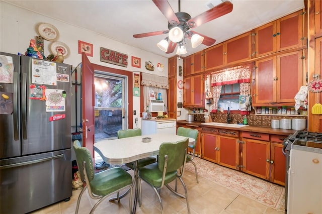 kitchen featuring appliances with stainless steel finishes, backsplash, ceiling fan, sink, and light tile patterned floors