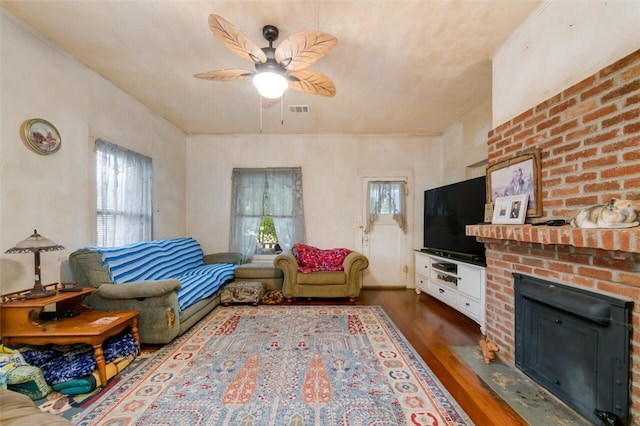 living room featuring ceiling fan, dark hardwood / wood-style flooring, a wealth of natural light, and a brick fireplace