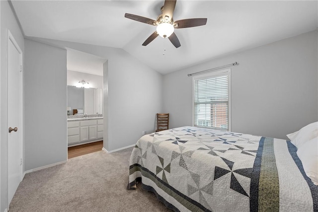 carpeted bedroom with baseboards, lofted ceiling, ceiling fan, a sink, and ensuite bathroom