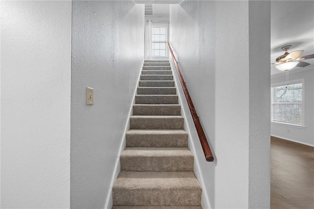 stairway with baseboards, a ceiling fan, and a textured wall