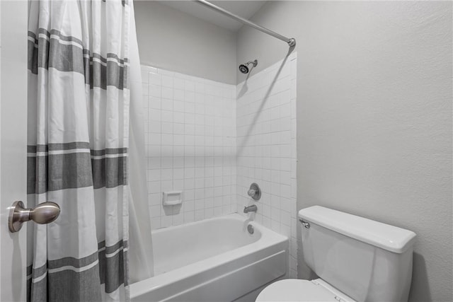 bathroom with toilet, a textured wall, and shower / bath combo