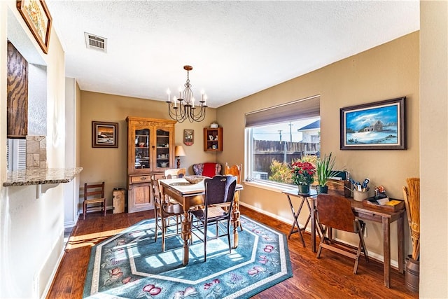 dining room with an inviting chandelier, dark hardwood / wood-style floors, and a textured ceiling