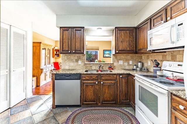 kitchen featuring sink, dark brown cabinetry, white appliances, and light stone counters