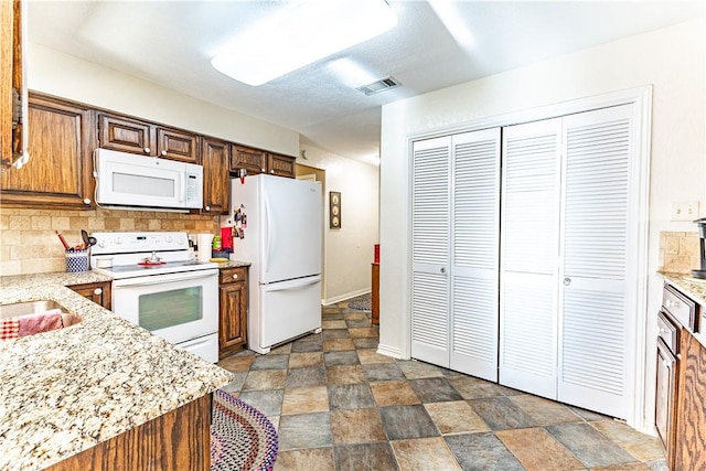 kitchen with light stone countertops, white appliances, and tasteful backsplash