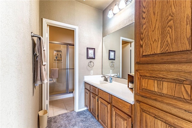 bathroom featuring a shower with shower door, vanity, and tile patterned flooring