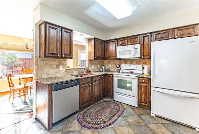 kitchen featuring sink, backsplash, white appliances, and light stone countertops