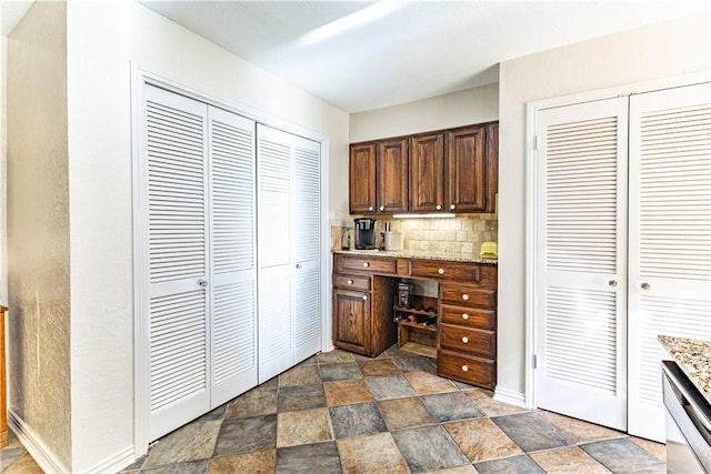 kitchen with stainless steel dishwasher, tasteful backsplash, and light stone counters