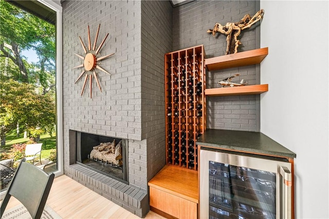 wine cellar with a healthy amount of sunlight, beverage cooler, brick wall, and light hardwood / wood-style floors