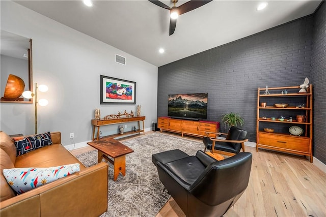 living room featuring ceiling fan, light hardwood / wood-style flooring, brick wall, and lofted ceiling