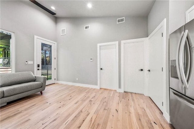 sitting room featuring plenty of natural light, high vaulted ceiling, and light hardwood / wood-style flooring