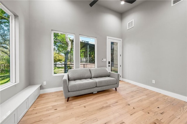 sitting room featuring ceiling fan, a high ceiling, and light hardwood / wood-style flooring