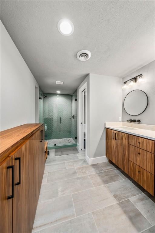 bathroom featuring vanity, a shower with shower door, and a textured ceiling