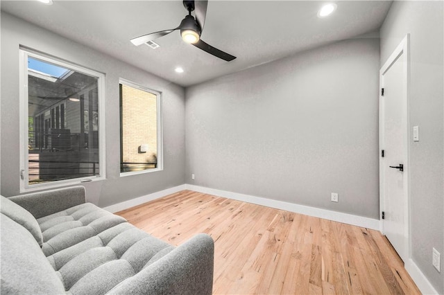 living area with wood-type flooring, a skylight, and ceiling fan