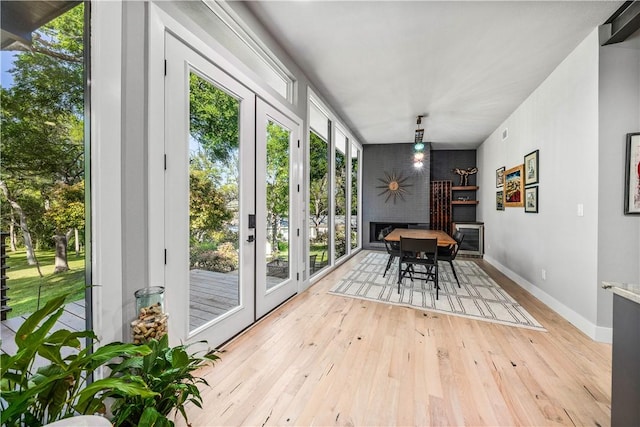 interior space featuring french doors, light wood-type flooring, and a brick fireplace