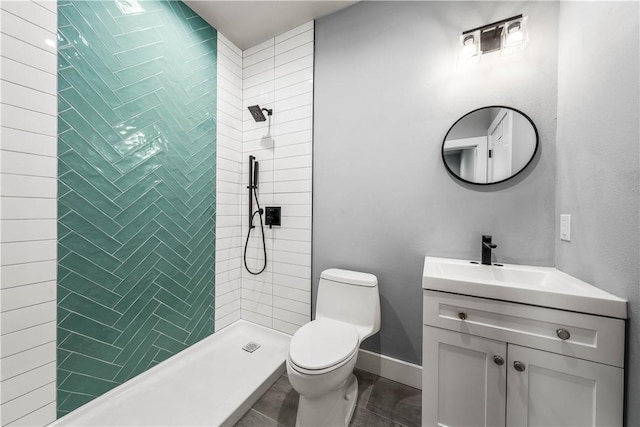 bathroom with tiled shower, tile patterned floors, vanity, and toilet