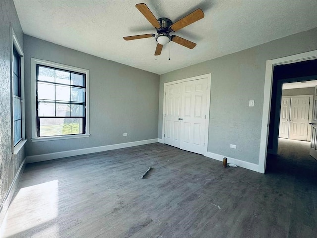 unfurnished bedroom with a textured ceiling, dark hardwood / wood-style flooring, a closet, and ceiling fan