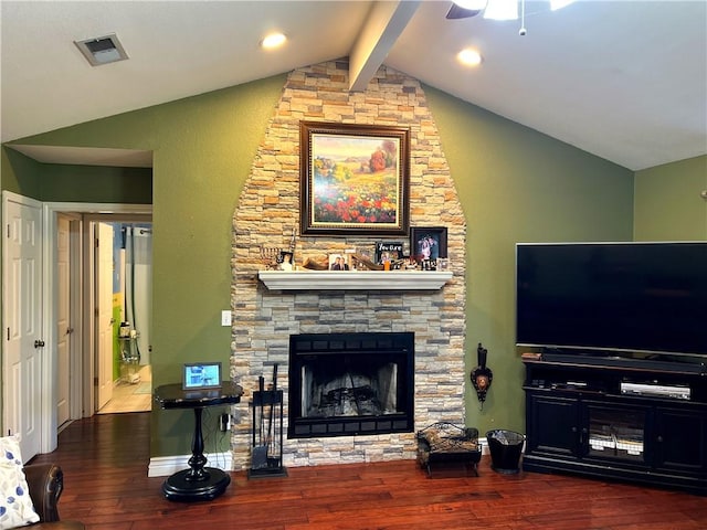 living room with vaulted ceiling with beams, hardwood / wood-style flooring, a stone fireplace, and ceiling fan