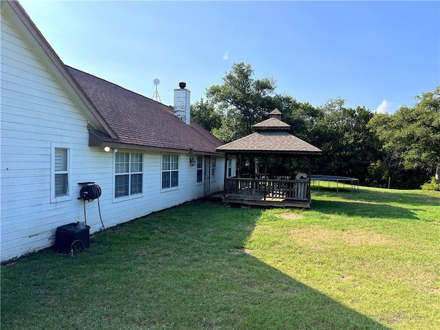 view of yard featuring a gazebo, a wooden deck, and a trampoline