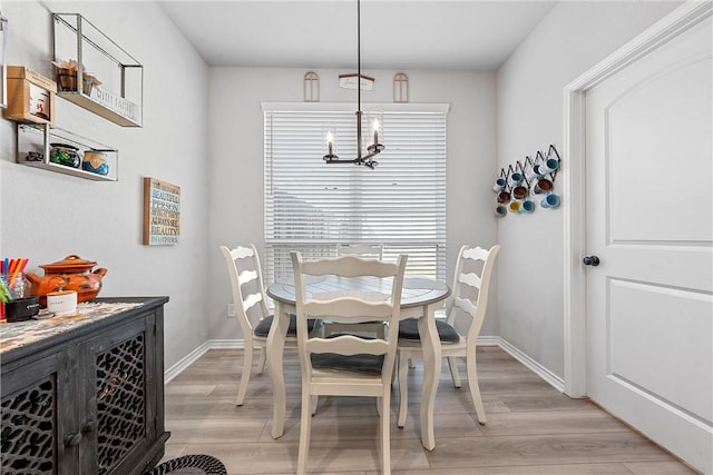 dining area with light wood-type flooring and a notable chandelier