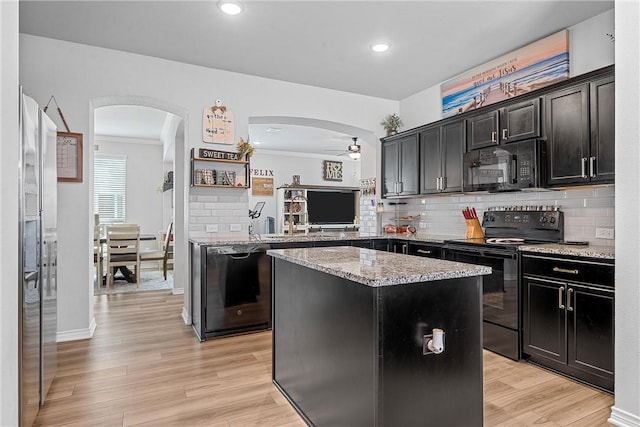 kitchen featuring light wood-type flooring, ceiling fan, crown molding, black appliances, and a center island