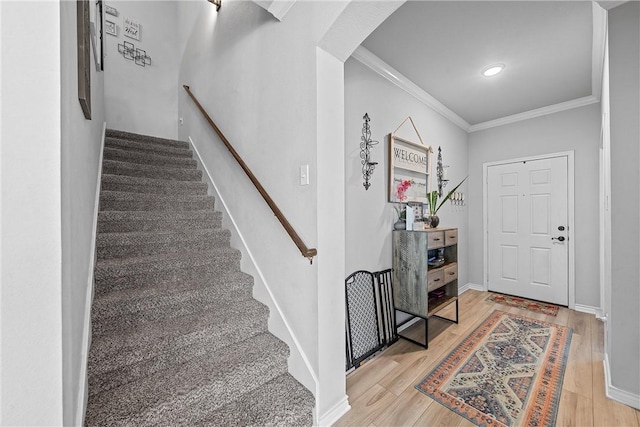 foyer with crown molding and light hardwood / wood-style floors