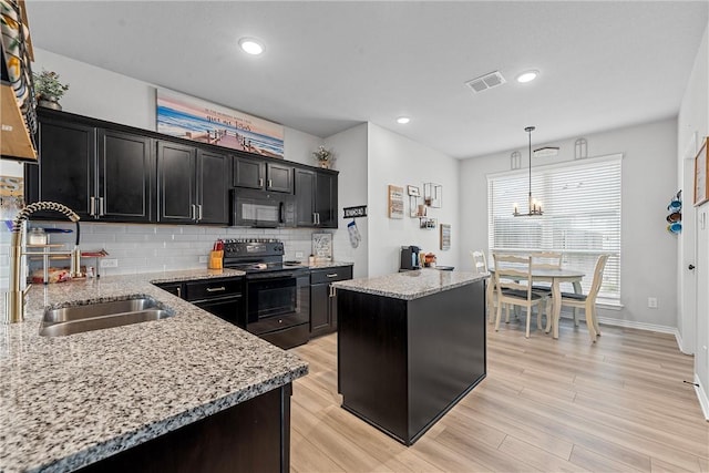 kitchen featuring pendant lighting, a center island, black appliances, sink, and light hardwood / wood-style floors