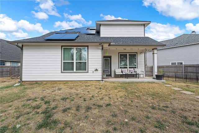 back of property featuring a lawn, a patio, an outdoor hangout area, and solar panels