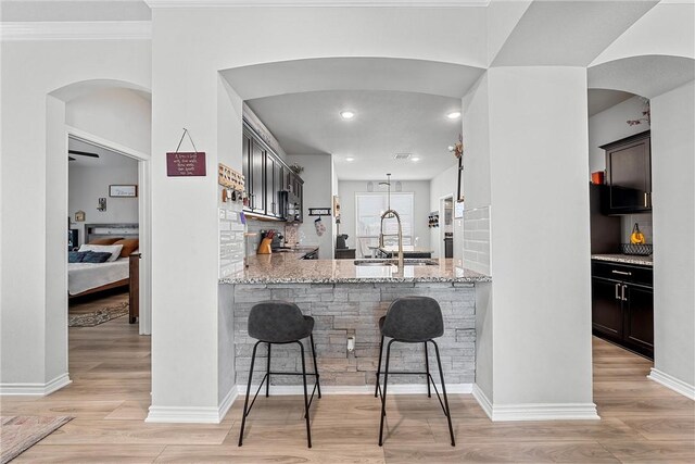 kitchen featuring kitchen peninsula, light stone counters, sink, and light hardwood / wood-style floors