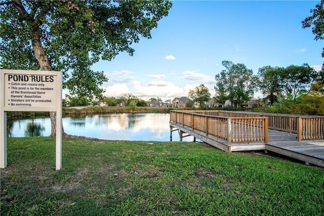 dock area featuring a deck with water view and a lawn