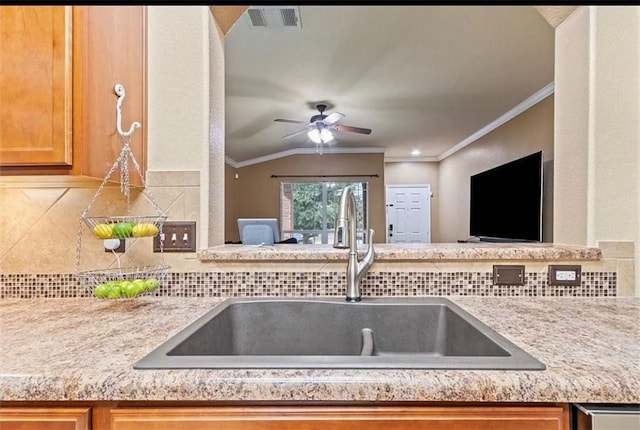 kitchen featuring ornamental molding, sink, backsplash, and ceiling fan