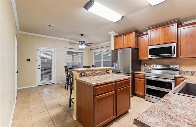 kitchen featuring tasteful backsplash, light tile patterned floors, stainless steel appliances, and a kitchen island