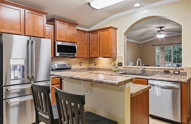 kitchen featuring sink, crown molding, appliances with stainless steel finishes, a kitchen bar, and vaulted ceiling