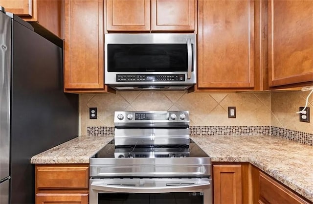 kitchen featuring tasteful backsplash, light stone countertops, and stainless steel appliances