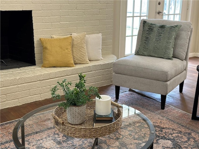 living area featuring hardwood / wood-style flooring and brick wall